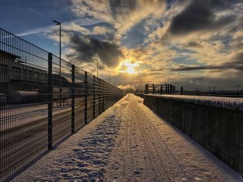 Footbridge against sky during sunset