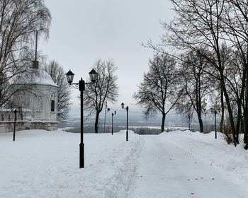 Bare trees on snow covered field against sky