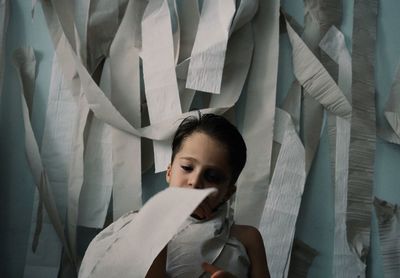 Boy wrapped in toilet paper standing at home