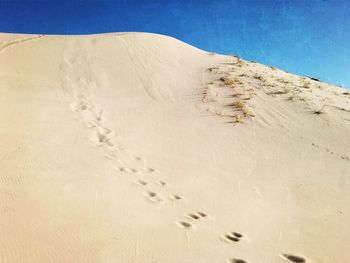 Low angle view of desert against clear blue sky