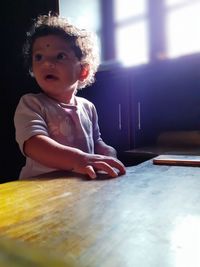 Portrait of cute boy sitting on table at home