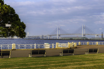 Park benches facing waterfront of port with long-span bridge