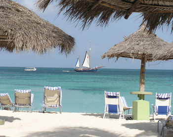 Lounge chairs on beach against blue sky