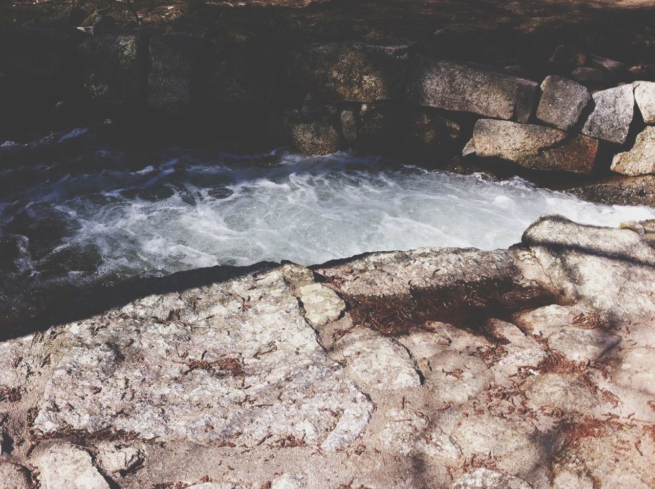 rock - object, water, nature, motion, high angle view, rock, animal themes, rock formation, one animal, flowing water, day, outdoors, stone - object, no people, beauty in nature, surf, waterfall, sunlight, flowing, splashing