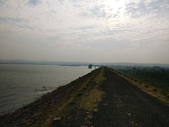 Scenic view of road by sea against sky