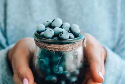 Woman holding bowl with frozen blueberry fruits. harvesting concept. female hands collecting berries