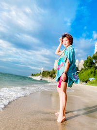 Full length of woman standing on beach against sky