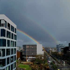 Rainbow over buildings in city against sky