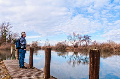 Man standing on pier over lake against sky