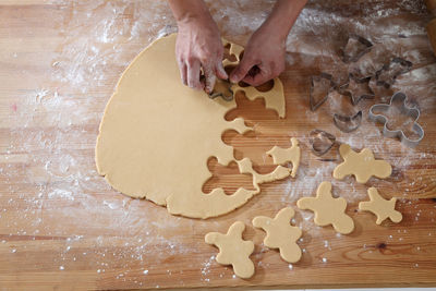 Cropped hands of chef cutting dough with pastry cutter at table