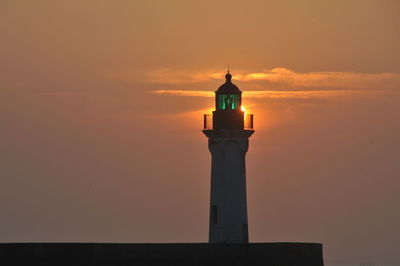 Silhouette of lighthouse against sky during sunset