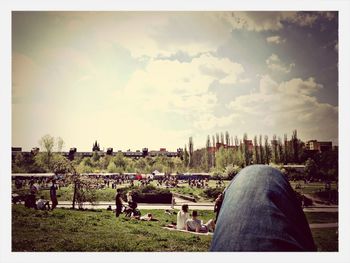 People on grassy field against cloudy sky