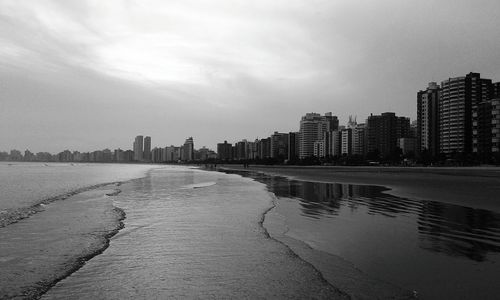 Buildings by beach against sky