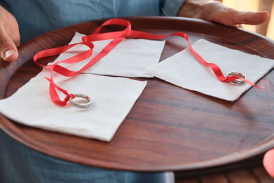 Engagement rings tied with red ribbon on a tray before wearing rings on fingers. engagement ceremony