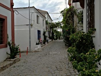 Footpath amidst houses and buildings against sky