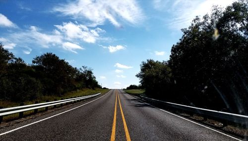 Road amidst trees against sky