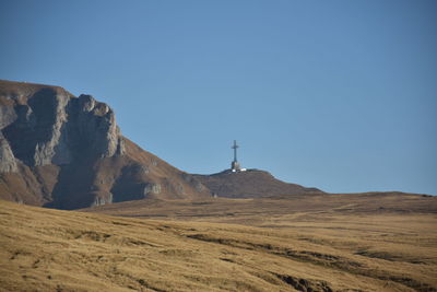 View of arid landscape against clear blue sky