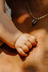 Cropped hand of baby on father chest