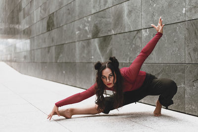 Full length of woman dancing on floor against wall