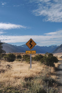 Road sign on field against sky