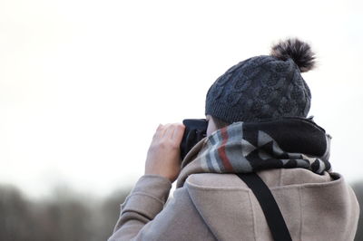 Rear view of woman photographing while standing against sky