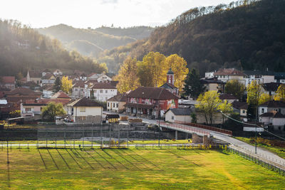 Scenic view of field by houses against sky