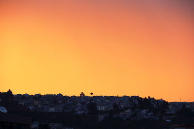 Buildings on mountain against clear sky during sunset