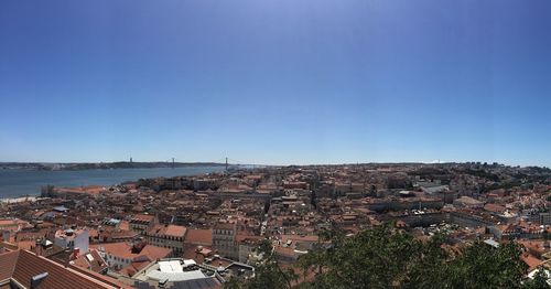 High angle view of townscape by sea against clear blue sky