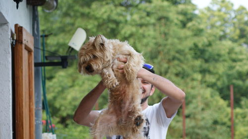 Young man playing with dog by house