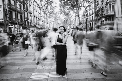 Portrait of woman standing on footpath in city