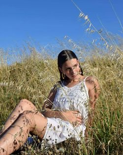 Young woman sitting amidst plants on field