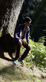 Portrait of young woman jumping on tree trunk