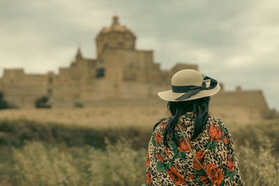 Rear view of woman standing against sky and mdina fortress 