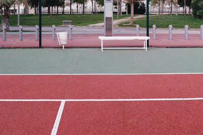 Bench on tennis court against fence