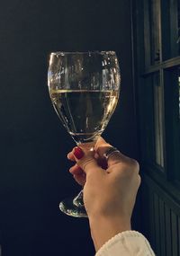 Midsection of woman holding glass against black background