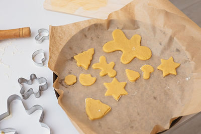 Round baking sheet with baking paper and raw christmas cookies of different shapes