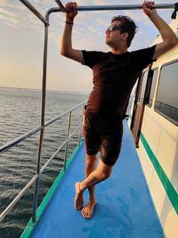 Full length of man standing on railing against sea