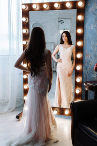Rear view of bride standing in front of illuminated mirror