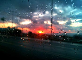 Close-up of wet window against sky during rainy season