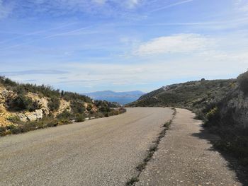 Road leading towards mountain against sky