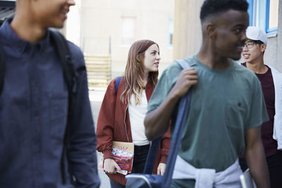 Male and female friends talking while walking at university campus