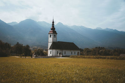 Building on field by mountains against sky