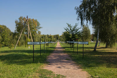 Footpath amidst trees on field against sky