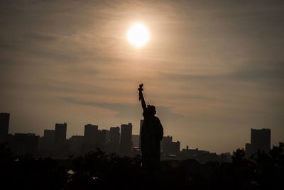 Silhouette of statue against cloudy sky during sunset