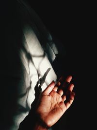 Close-up of couple holding hands against black background