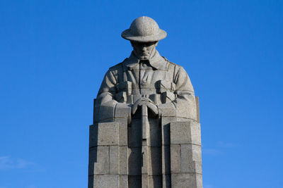 Low angle view of statue against blue sky