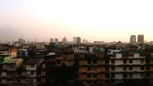 Buildings in city against clear sky during sunset