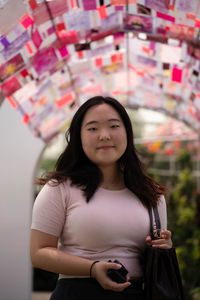 Portrait of young woman standing in city
