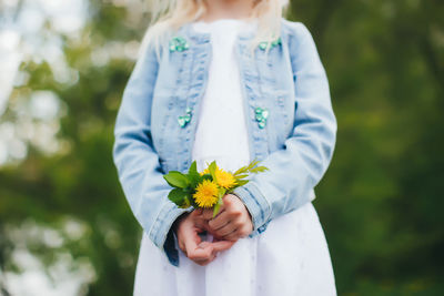 Midsection of woman holding white flower