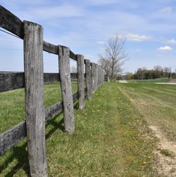 Wooden fence on field against sky